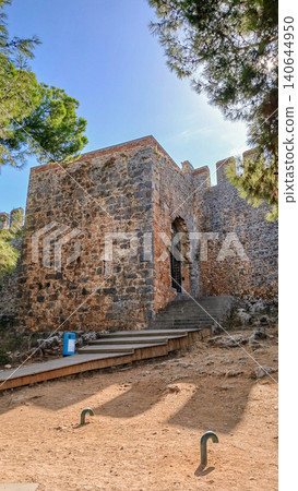 Ancient stone fortress entrance surrounded by trees and blue sky in Alanya, Turkey Ancient stone fortress entrance surrounded by trees and blue sky in Alanya, Turkey 140644950