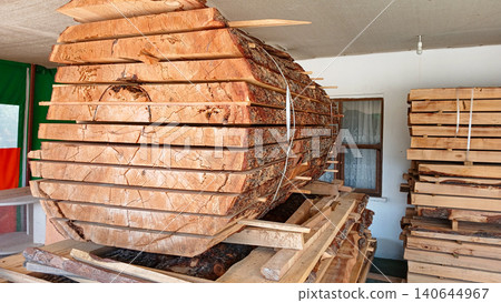 Large wooden log stacked in workshop with tools and equipment visible Large wooden log stacked in workshop with tools and equipment visible 140644967