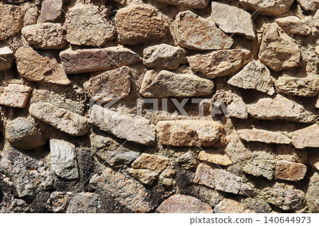 A wall built with rough stone masonry. A wall built with rough stone masonry. 140644973