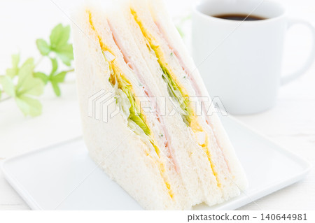 一份美味的火腿、雞蛋和生菜三明治,再來一杯咖啡。 一份美味的火腿、雞蛋和生菜三明治,再來一杯咖啡。 140644981