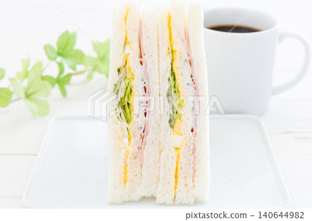 A delicious ham, egg, and lettuce sandwich and coffee. A delicious ham, egg, and lettuce sandwich and coffee. 140644982