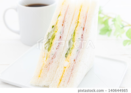 一份美味的火腿、雞蛋和生菜三明治,再來一杯咖啡。 一份美味的火腿、雞蛋和生菜三明治,再來一杯咖啡。 140644985