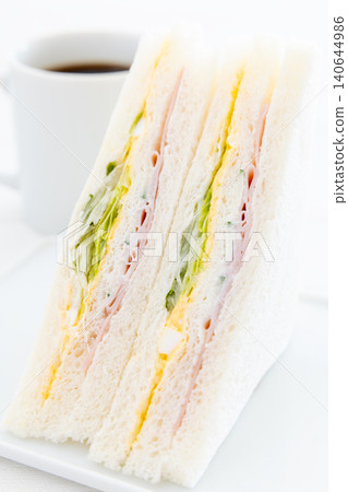 一份美味的火腿、雞蛋和生菜三明治,再來一杯咖啡。 一份美味的火腿、雞蛋和生菜三明治,再來一杯咖啡。 140644986