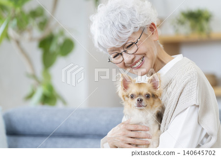 Senior woman holding her pet dog Senior woman holding her pet dog 140645702
