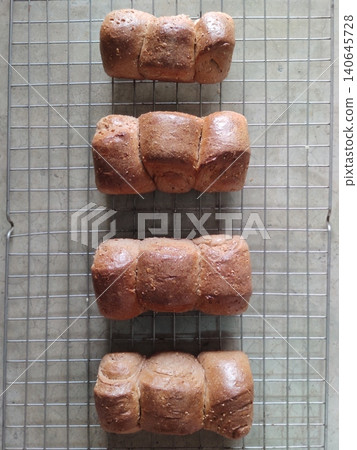 Freshly Baked Warm Chocolate Bun Bread Loaves Arranged on Cooling Rack Showing Soft Texture and Golden Brown Crust for Bakery Presentation Freshly Baked Warm Chocolate Bun Bread Loaves Arranged on Cooling Rack Showing Soft Texture and Golden Brown Crust for Bakery Presentation 140645728