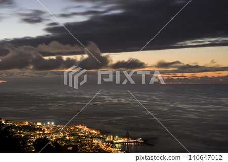 Coastal city lights illuminating ocean during sunset dusk Coastal city lights illuminating ocean during sunset dusk 140647012