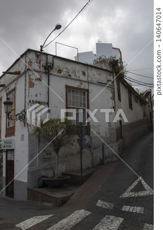 Old peeling building on urban cobblestone street corner Old peeling building on urban cobblestone street corner 140647014