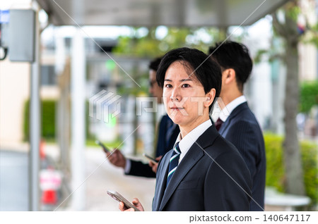 A man in a suit waiting for a bus at a bus stop. A man in a suit waiting for a bus at a bus stop. 140647117