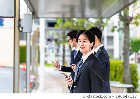 一名身穿西裝的男子在公車站等車。 一名身穿西裝的男子在公車站等車。 140647118