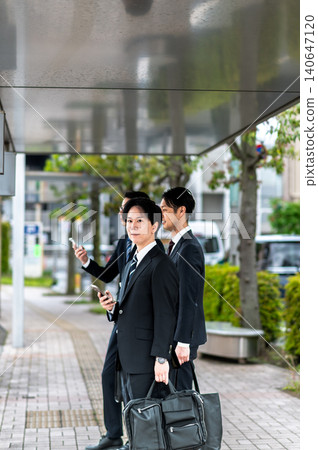 A man in a suit waiting for a bus at a bus stop. A man in a suit waiting for a bus at a bus stop. 140647120