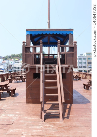 Wooden Deck Structure with Blue Canopy on Boardwalk Wooden Deck Structure with Blue Canopy on Boardwalk 140647358