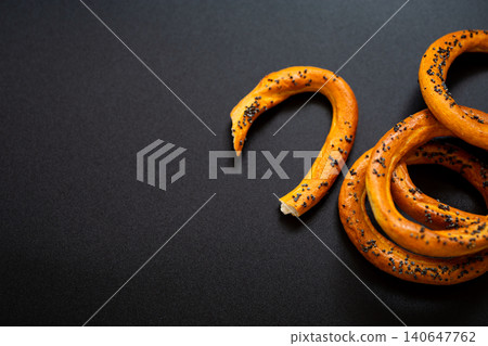 Crunchy bakery rings with poppy seeds on black backdrop Crunchy bakery rings with poppy seeds on black backdrop 140647762