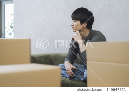 A young man sitting surrounded by cardboard boxes; moving image. A young man sitting surrounded by cardboard boxes; moving image. 140647851