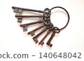 Collection of old metal keys on a ring lying on a flat surface in a bright setting during daylight 140648042
