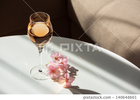 Rose wine glass on white table with pink flowers Rose wine glass on white table with pink flowers 140648601