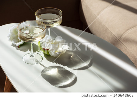 Two coupe glasses with sparkling wine and white flowers Two coupe glasses with sparkling wine and white flowers 140648602