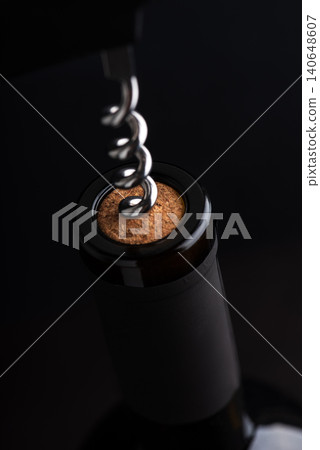 Corkscrew opening a wine bottle with dark background Corkscrew opening a wine bottle with dark background 140648607