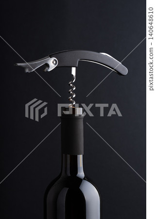 Corkscrew opening a bottle of red wine, starting to pull cork 140648610