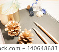 A pine cone and a pencil placed on an antique-style table. 140648683