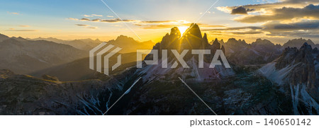 Panoramic view of Tre Cime di Lavaredo glowing in golden sunset light in the Italian Dolomites. Dramatic alpine landscape with rugged peaks, winding trails and breathtaking scenery. Panoramic view of Tre Cime di Lavaredo glowing in golden sunset light in the Italian Dolomites. Dramatic alpine landscape with rugged peaks, winding trails and breathtaking scenery. 140650142