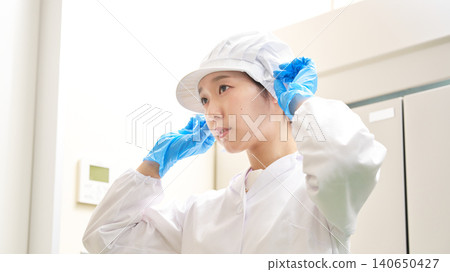 Female workers check their appearance before starting work at a food factory. Female workers check their appearance before starting work at a food factory. 140650427