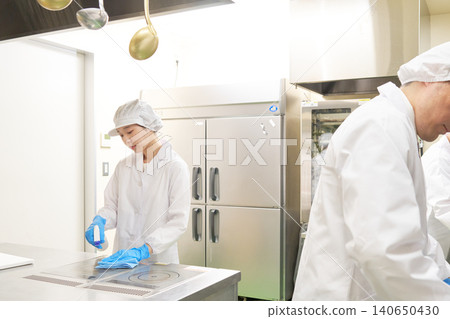 身穿白大褂的工作人員正在清潔廚房設備。 身穿白大褂的工作人員正在清潔廚房設備。 140650430