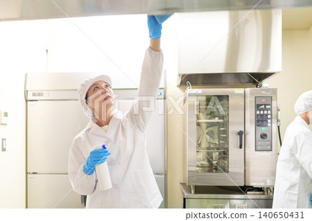 Staff in white coats cleaning kitchen equipment. Staff in white coats cleaning kitchen equipment. 140650431