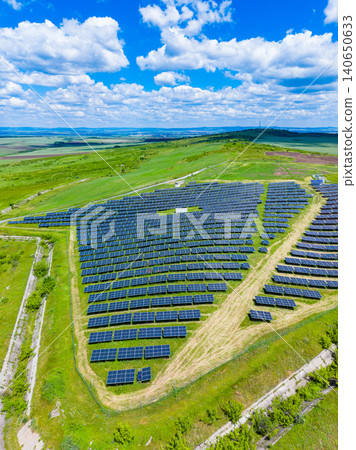 Bright sky above photovoltaic array. Industrial scale solar panel installation under clear blue sky. Dense rows of solar modules with maintenance paths on open land Bright sky above photovoltaic array. Industrial scale solar panel installation under clear blue sky. Dense rows of solar modules with maintenance paths on open land 140650633