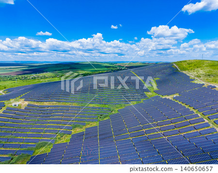Photovoltaic field contouring rugged hillside with grassy pathways. Aerial perspective of solar panels on steep terrain with natural greenery and reflective surfaces Photovoltaic field contouring rugged hillside with grassy pathways. Aerial perspective of solar panels on steep terrain with natural greenery and reflective surfaces 140650657