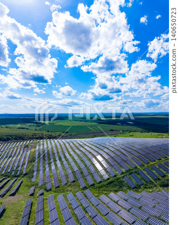 Large solar farm located on a hillside under a bright blue sky with scattered clouds capturing sunlight during the daytime Large solar farm located on a hillside under a bright blue sky with scattered clouds capturing sunlight during the daytime 140650723