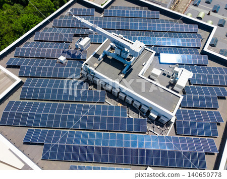 Solar panels cover the roof of a large building in a city, showcasing renewable energy technology in action during bright daylight 140650778