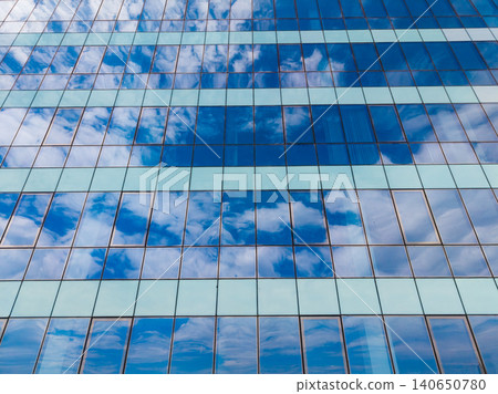 Reflections of clouds and sky on the glass windows of a modern building during a sunny day in a city Reflections of clouds and sky on the glass windows of a modern building during a sunny day in a city 140650780