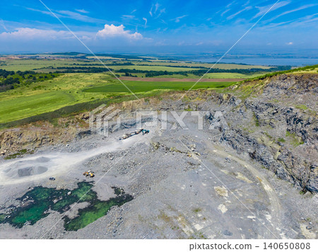 Granite quarry site showing machinery and landscape with blue sky and clouds in daytime Granite quarry site showing machinery and landscape with blue sky and clouds in daytime 140650808