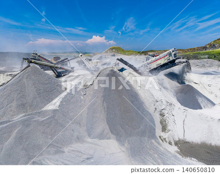 Granite quarry site showing machinery and piles of stone material during the day in sunny weather with blue skies Granite quarry site showing machinery and piles of stone material during the day in sunny weather with blue skies 140650810