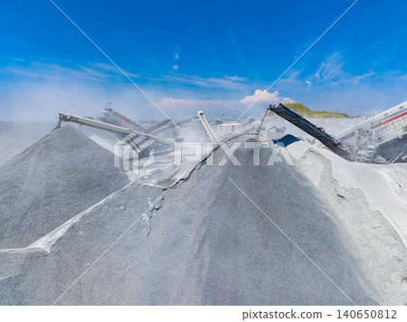 Granite quarry workers carry out operations to process stone in a busy work site under clear blue skies during the day Granite quarry workers carry out operations to process stone in a busy work site under clear blue skies during the day 140650812