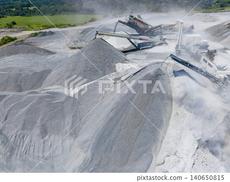 Granite quarry operation in a remote location with heavy machinery processing stone during daytime hours Granite quarry operation in a remote location with heavy machinery processing stone during daytime hours 140650815
