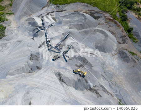 Granite quarry in operation with heavy machinery moving materials and processing stone at a site during daylight hours Granite quarry in operation with heavy machinery moving materials and processing stone at a site during daylight hours 140650826