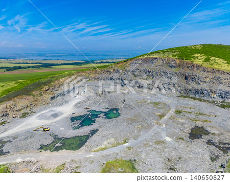 View of a granite quarry showing active worksite and natural landscape in a rural area under a clear blue sky View of a granite quarry showing active worksite and natural landscape in a rural area under a clear blue sky 140650827