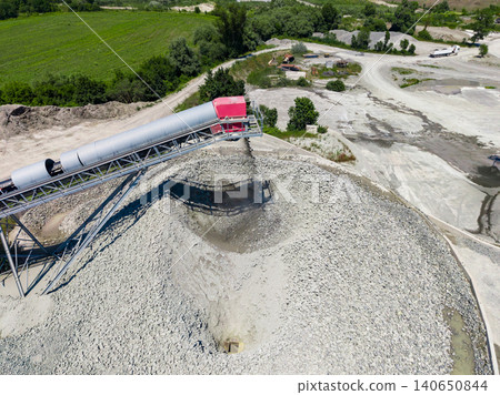 Granite quarry site showing large piles of crushed stone and machinery during daytime operations in a work area Granite quarry site showing large piles of crushed stone and machinery during daytime operations in a work area 140650844