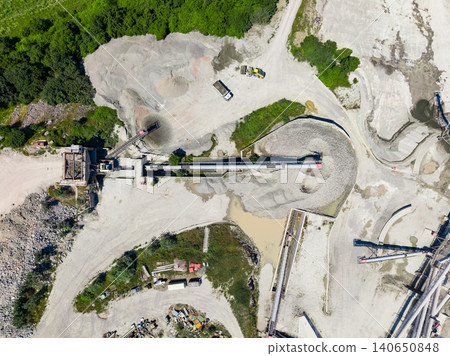 Granite quarry operation site with equipment and trucks working in processing area during daylight hours in remote location Granite quarry operation site with equipment and trucks working in processing area during daylight hours in remote location 140650848