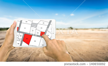 Man holding a tablet looking at lots of lands. Land plot management - real estate concept with vacant land for building construction and housing subdivision for sale, rent, buy, or investment. Man holding a tablet looking at lots of lands. Land plot management - real estate concept with vacant land for building construction and housing subdivision for sale, rent, buy, or investment. 140650892