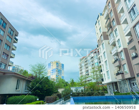 Cloudy weather over modern buildings and a small blue pool in an urban setting during late afternoon Cloudy weather over modern buildings and a small blue pool in an urban setting during late afternoon 140650958