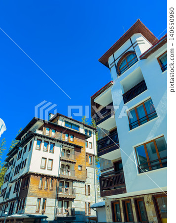Buildings stand against a clear blue sky in a mountain area during daytime, showcasing architectural design and materials in a scenic setting Buildings stand against a clear blue sky in a mountain area during daytime, showcasing architectural design and materials in a scenic setting 140650960