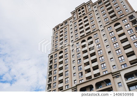 Soaring residential tower reaching toward sky with layered balconies and arched openings, evoking ambition, height and metropolitan energy for lifestyle and development use Soaring residential tower reaching toward sky with layered balconies and arched openings, evoking ambition, height and metropolitan energy for lifestyle and development use 140650998