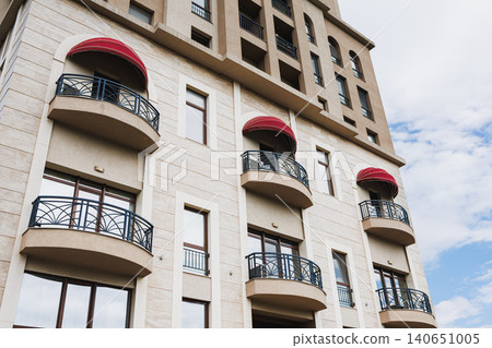 Charming city balcony. Stylish residence featuring iron balconies and large windows. Refined urban dwelling showcasing wrought iron railings and vibrant red window coverings Charming city balcony. Stylish residence featuring iron balconies and large windows. Refined urban dwelling showcasing wrought iron railings and vibrant red window coverings 140651005