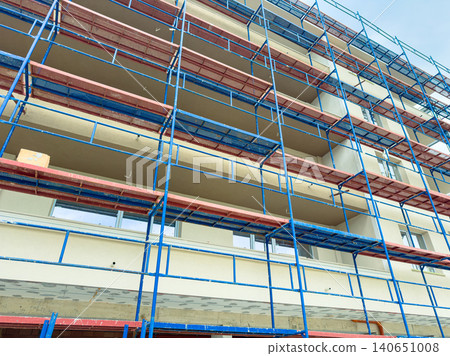 Construction work takes place on a building with scaffolding in an urban area during a cloudy day Construction work takes place on a building with scaffolding in an urban area during a cloudy day 140651008