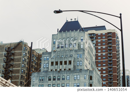 Buildings stand tall against the sky in a city scene with various architectural styles and designs during a cloudy day in the urban area Buildings stand tall against the sky in a city scene with various architectural styles and designs during a cloudy day in the urban area 140651054