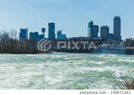 View of Niagara Falls with city skyline and rushing water under a clear sky during the daytime View of Niagara Falls with city skyline and rushing water under a clear sky during the daytime 140651061