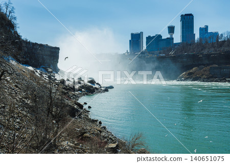 View of Niagara Falls with buildings in the background and water flowing from the falls during daylight hours View of Niagara Falls with buildings in the background and water flowing from the falls during daylight hours 140651075