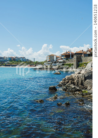 Village by water with cheerful surroundings. Sundrenched coastal hamlet with shimmering surfaces and peaceful breezes creating perfect vacation ambiance for travelers Village by water with cheerful surroundings. Sundrenched coastal hamlet with shimmering surfaces and peaceful breezes creating perfect vacation ambiance for travelers 140651218